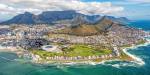 Cape Town seen from the air. Mountains and clouds in the background, the sea in the foreground. There is partial sunshine over the city.