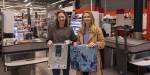 To unge kvinner i en butikk holder opp plastpose og handelnett