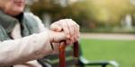 Blurred lone elderly male on bench, hands in fokus