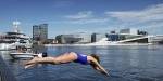 Woman diving into the Oslo Fjord with the opera house in the background.